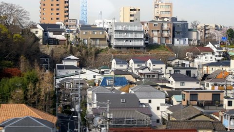 Tokyo, Japan - April 5, 2019: Shinkansen bullet train in morning moving in slow motion with cityscape skyline of residential buildings in Toshima city