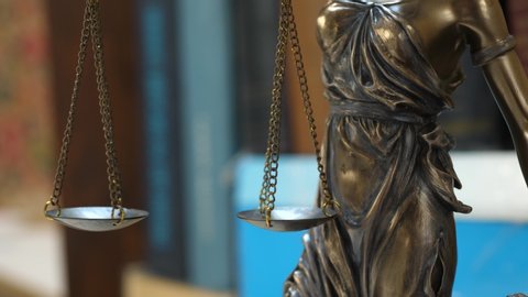 Statue of Themis or Lady Justice on Bookshelf Background. Law Firm or Business Concept
