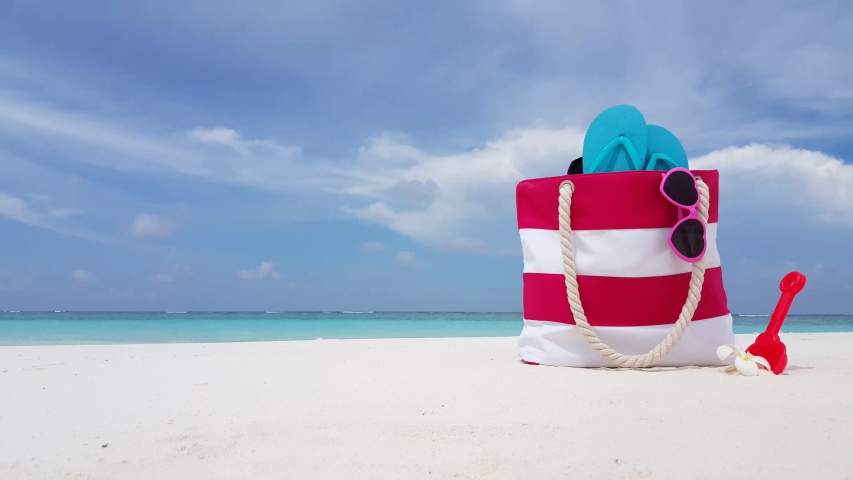 Beach bag filled with beach stuff, flipflops, sandals, sunglasses, shovel Royalty-Free Stock Footage #1042303957