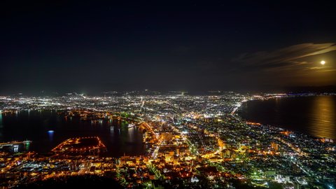 Time-lapse sunset to night, view from Mt. Hakodate observatory, big bright moon light up the sea, golden reflection on surface. Famous scenic spot in the world. Hokkaido, Japan. 4K UHD