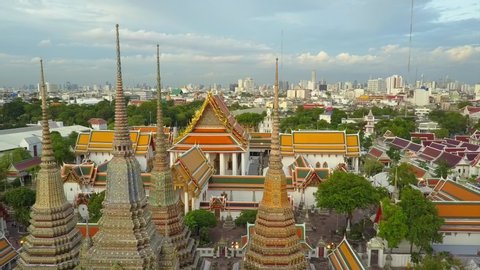 Bangkok temple Wat Phra Kaew in beautiful drone view in 4K. Aerial shot of amazing Thai Buddhist temple. Unique perspective close over golden roof skyline background. Wat Pho city center golden light