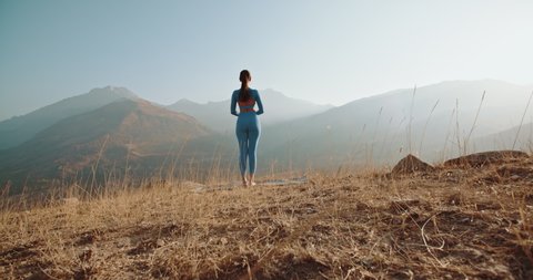 Athlete training yoga. Young healthy girl having a yoga meditation session in mountains during sunrise - healthy lifestyle, zen concept 4k footage