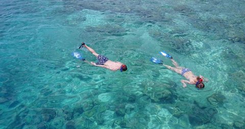 Couple Snorkeling In Clear Tropical Blue Water exploring the coral reef, maldives