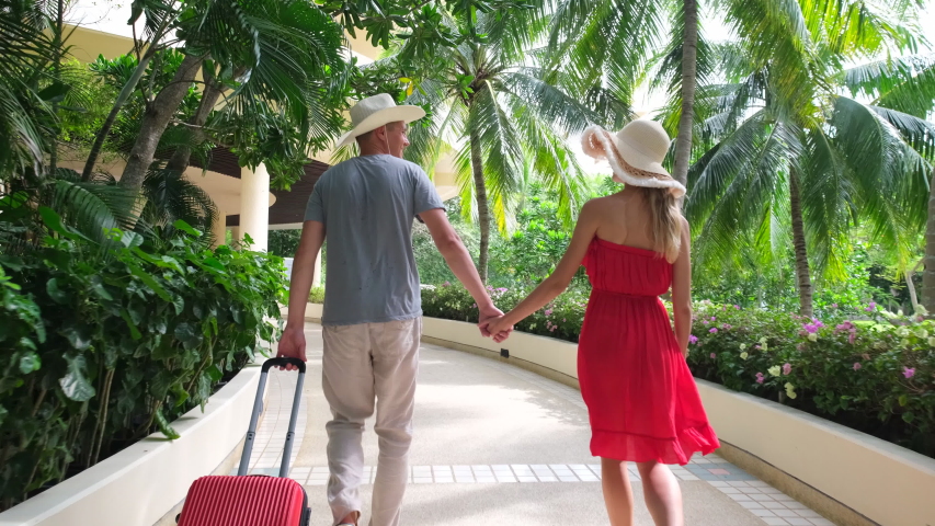 Couple traveler man and woman girl in red dress with suitcase at luxury resort. tourists in tropical hotel. travel tourism beach vacation happy family holiday sweethearts love honeymoon slow-mo, 4 K Royalty-Free Stock Footage #1042326145