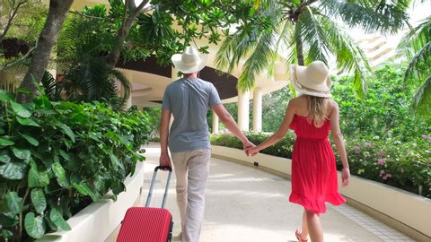 Couple traveler man and woman girl in red dress with suitcase at luxury resort. tourists in tropical hotel. travel tourism beach vacation happy family holiday sweethearts love honeymoon slow-mo, 4 K
