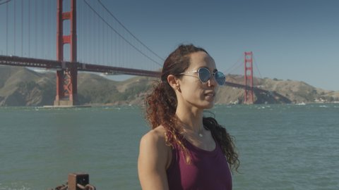 Slow motion tracking shot of woman walking at waterfront near Golden Gate Bridge / San Francisco, California, United States