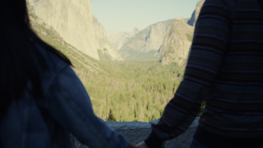 Couple admiring scenic view of mountain range / Yosemite Valley, California, United States