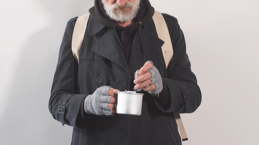 Portrait of a homeless beggar in Studio on white background, pulls bills out of Cup for money.