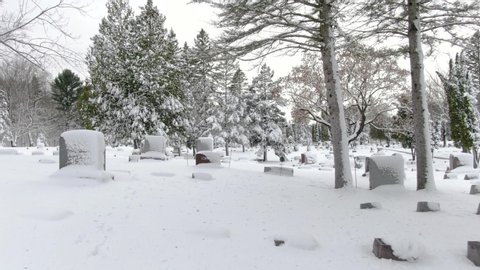 Beautiful snow covered cemetery, graveyard, tombstones, after blizzard, aerial drone view.  This is very useful footage because virtually all of the inscriptions are covered.