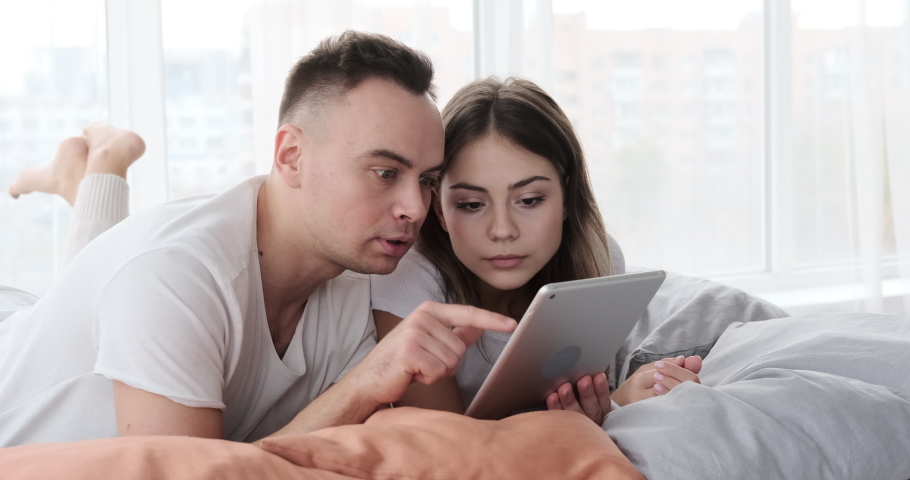 Couple astonished using digital tablet in bed | Shutterstock HD Video #1042351309