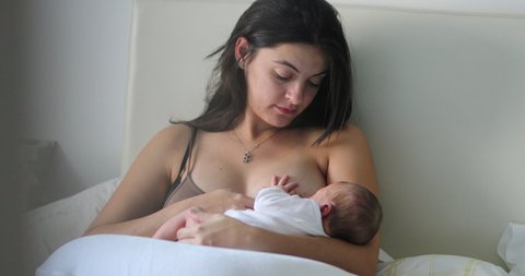 Mother breastfeeding newborn baby in the morning