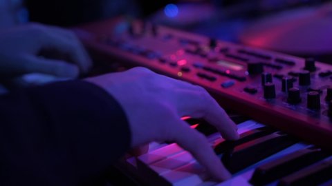 A pianist and a drummer perform modern music at a party. Men in black perform jazz, soul, chill out songs at nightclub. Musicians play instruments under muffled lighting, close-up. Relaxing atmosphere