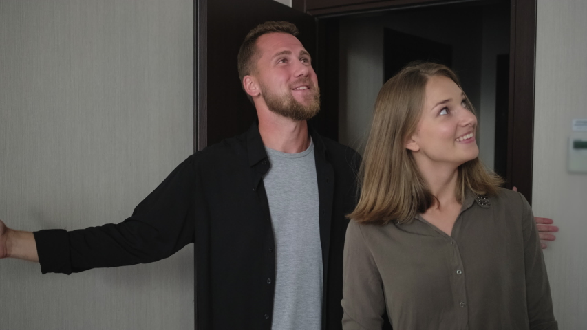 Slow motion shot of young family couple walking into the new apartment. Happy man and woman are delighted with their comfortable flat