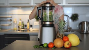 Woman making green smoothies with blender at home in kitchen, healthy eating lifestyle concept, slow motion video