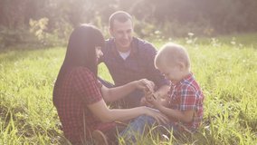 happy family teamwork outdoors concept outdoors slow motion video. mom dad and a son lifestyle in nature are sitting on the grass have fun. playing mom girl dad man and son boy happy family