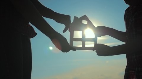 happy family construction house teamwork concept. Mom and son holding home a paper house in his hands at sunset silhouette sunlight. life symbol ecology video. boy and lifestyle girl hold paper home