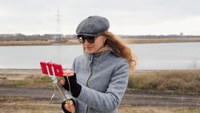 Frozen girl blogger turns on live stream online on phone, greets viewers. A woman in a coat in the open air talking in headphones conducts a live broadcast and smiles. Technology and lifestyle concept