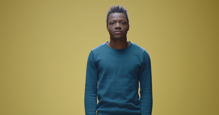 Medium shot of a cheerful young man crossing his arms while looking at camera