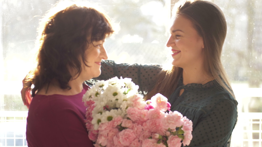 Young adult woman daughter hugging happy middle aged mom, embracing bonding congratulating mature mum with mothers day concept, presenting flowers, celebrating together Royalty-Free Stock Footage #1042384501