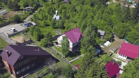 View from drone on a small beautiful village with modern cottages and green trees. Clip. Summer countryside aerial view of the houses in ecological area.