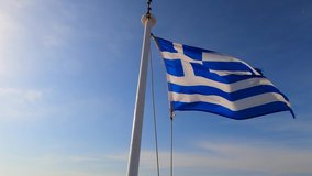 Video of Greek flag waving on slightly cloudy blue sky as seen in Greek island of the Aegean