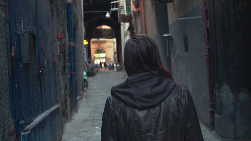 Young Caucasian Woman Walks Alone Down a Run Down Old Alleyway in the City of Naples, Italy.
