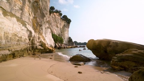 Point of view: Strolling down stingray bay's beach with white sandstone cliffs and emerald waves. Hahei, Coromandel,  North Island. New Zealand.