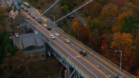 Cinematic aerial pulls out to show Bear Mountain Bridge traffic with Autumn foliage in Hudson River Valley