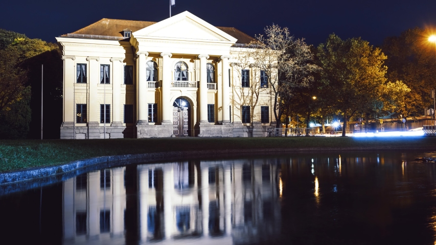Night timelapse of Prinz-Carl-Palais between Munich English Garden and Hofgarten illuminated water reflection and light trails