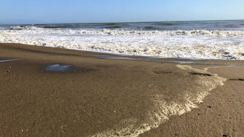 Foamy waves breaking on a sandy beach in spain