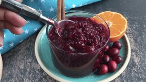 Homemade cranberry orange sauce or jam with cinnamon in a glass. 4k