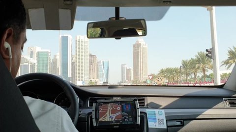 DOHA, Qatar - November 2019
Shot from taxi in Doha on highway, view on modern town. Driver in shot. Sunny day