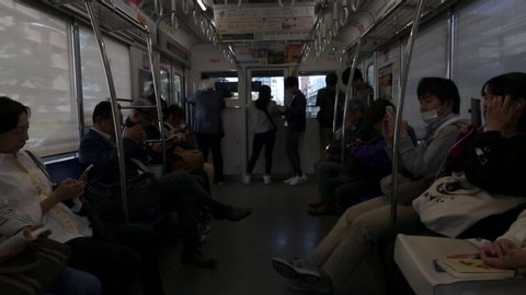 TOKYO, JAPAN - OCTOBER 30, 2019: People are travelling in Tokyo Train to Shinjuku. Seibu Shinjuku Line. People Are Sitting and Playing with Mobile Phones, Reading Books. 