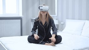 Attractive young woman use glasses of virtual reality at home sitting on bed look around relaxation vr device entertainment female girl digital experience future relax studio close up slow motion