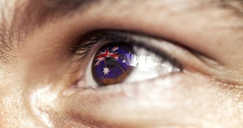 man with brown eyes in close up, the flag of Australia in iris with wind motion. video concept