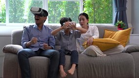 Father, mother and sons playing video games with virtual reality glasses and sons  having fun with new technology online.