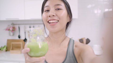 Asian blogger lady make vlog how to diet and lost weight, Young indian female using smartphone recording when she drinking apple juice in the kitchen. Lifestyle influencer women healthy food concept.