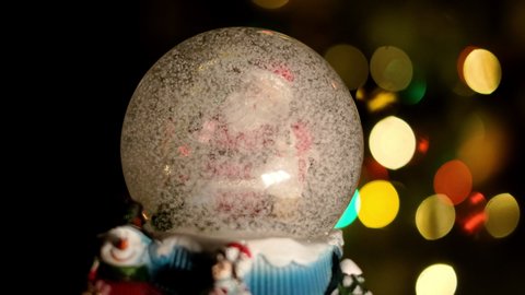 Christmas Magic Ball With Santa And The Boy Inside. Santa Hugs Little Boy. In The Background Are Multicolored Rays That Glow In The Dark. In The Ball The Effect Of The Circling Snow.