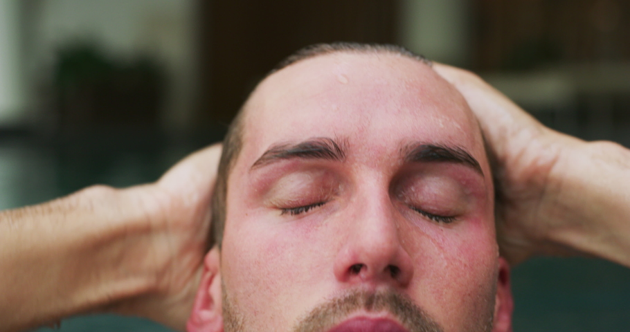 Close up of an young man is enjoying and having relax in an indoor swimming pool in a luxury wellness center.
