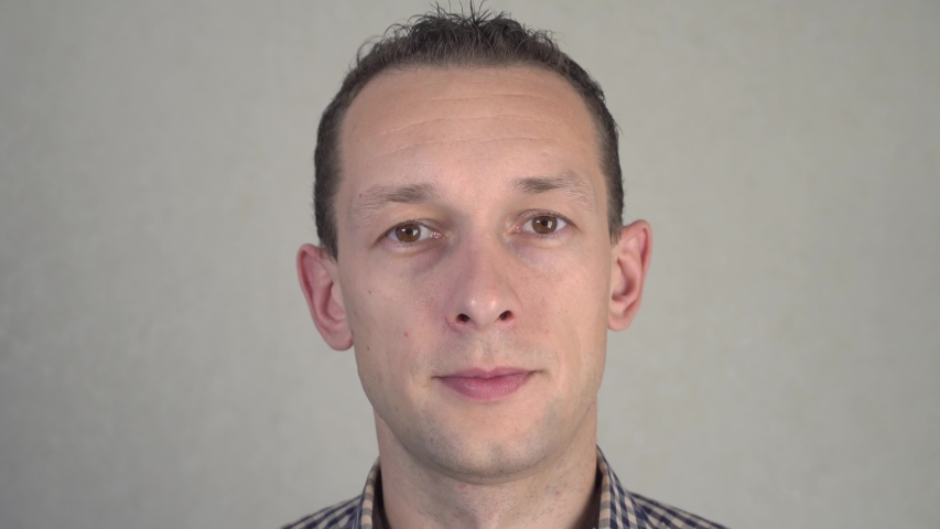 Portrait of a cheerful young man holding heart shapes hiding eyes smiling. The concept of people, emotions and feelings of valentines day