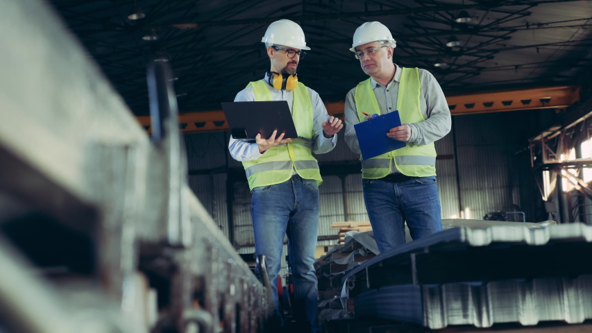 Professional heavy Industry Engineers. Male workers are talking in a plant unit with building supplies