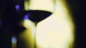 Close up slow motion shot, wine glass with party lights in background inside club. Party, event, celebration concept.