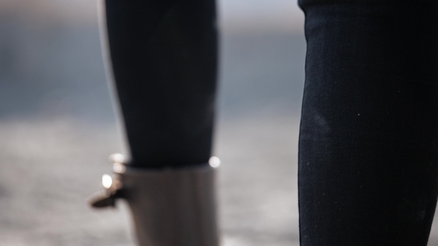 view from the back of the dirty boots of a woman walking along a wasteland
