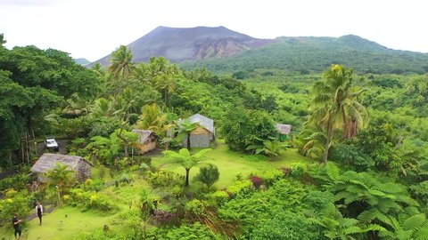 VANUATU - CIRCA 2019 - very good aerial over a jungle village on the island of Tanna reveals Mt. Yasur volcano in the distance, Vanuatu.