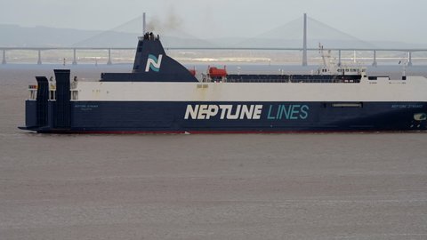 Bristol,Somerset/UK-12/07/2019: Vehicle carrier Neptune Dynamis passes before the Severn Crossing Bridge in Avonmouth carrying cars into Portbury docks from the EU. She was built in 2002