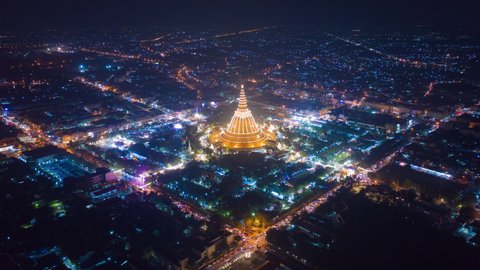 Hyper lapse of aerial top view of Phra Pathommachedi temple at night. The golden buddhist pagoda with residential houses, urban city of Nakorn Pathom district, Thailand. Holy Thai architecture.