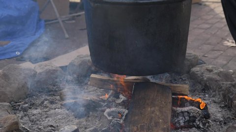Tilt up on steaming cauldron slow motion outside