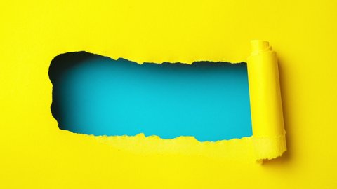 Yellow paper is torn over blue background for message, stop motion, animation. 