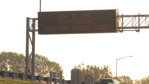 AMERICAN SOUTH - CIRCA 2010s - A humorous highway sign on a hot day says 100 degrees is the temperature not the speed limit.