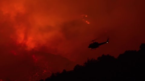 SANTA BARBARA, CALIFORNIA - CIRCA 2010s - a helicopter makes a dramatic water drop at night responding to the Cave Fire near Santa Barbara.